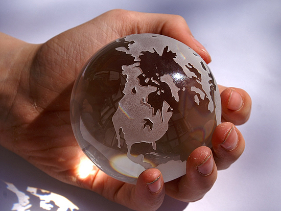 kleine Glaskugel mit Weltkarte wird in der Hand gehalten 