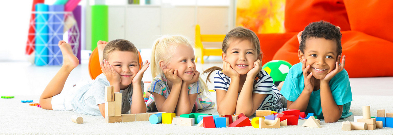 4 Kinder auf einem Spielteppich im Kindergarten
