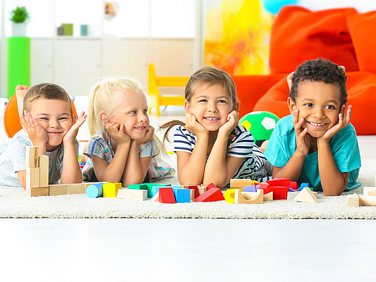 4 Kinder auf einem Spielteppich im Kindergarten