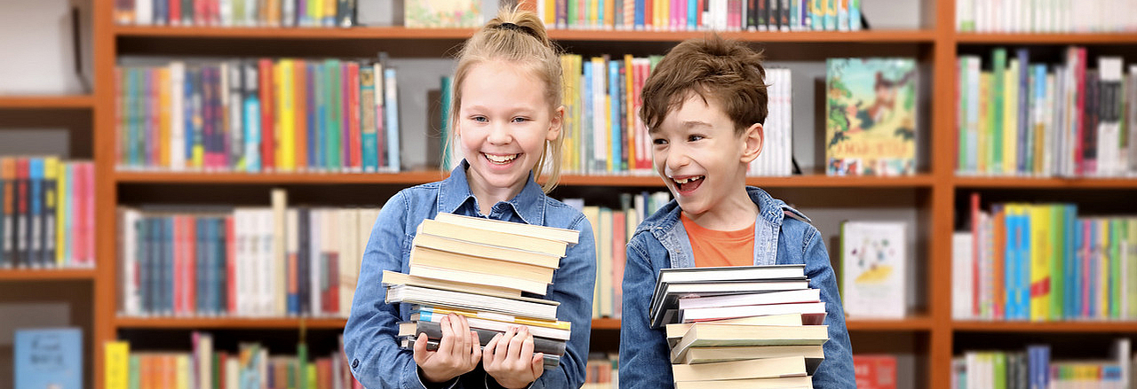 Kinder mit einem Bücherstapel in einer Bibliothek