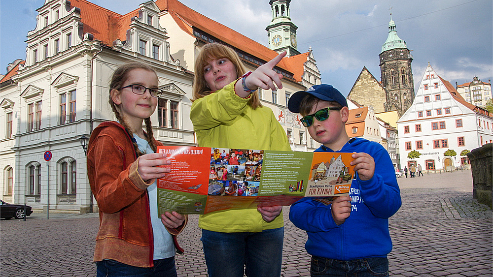 Kinderstadtplan Drei Kinder schauen sich den Kinderstadtplan für Pirna an