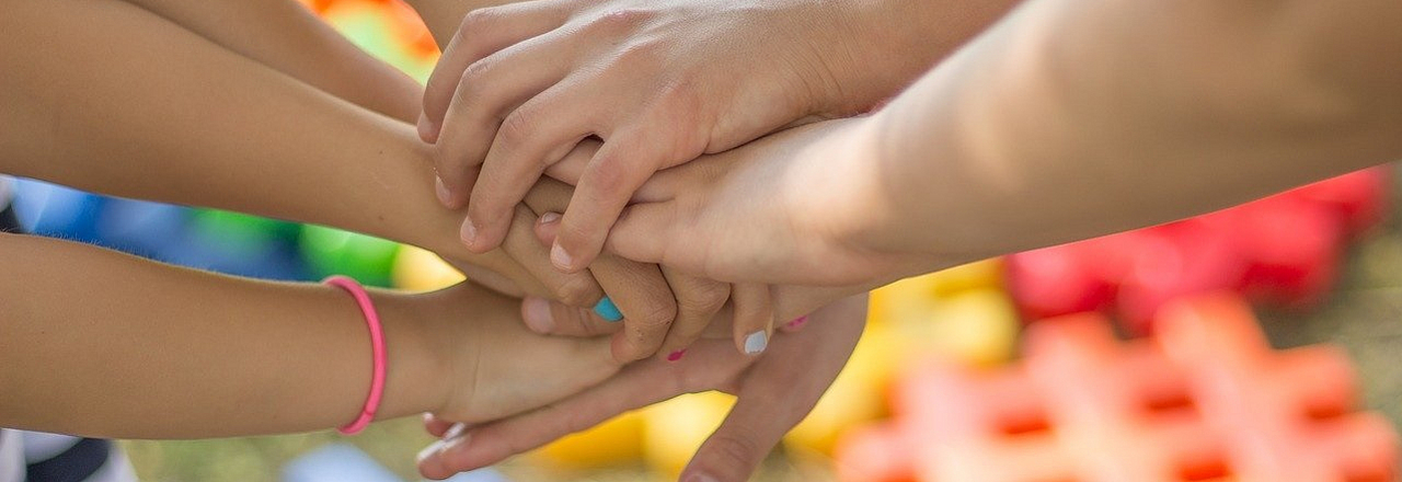 Mehrere Hände treffen sich in der Mitte um Zusammenhalt abzubilden