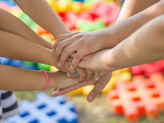 Mehrere Hände treffen sich in der Mitte um Zusammenhalt abzubilden