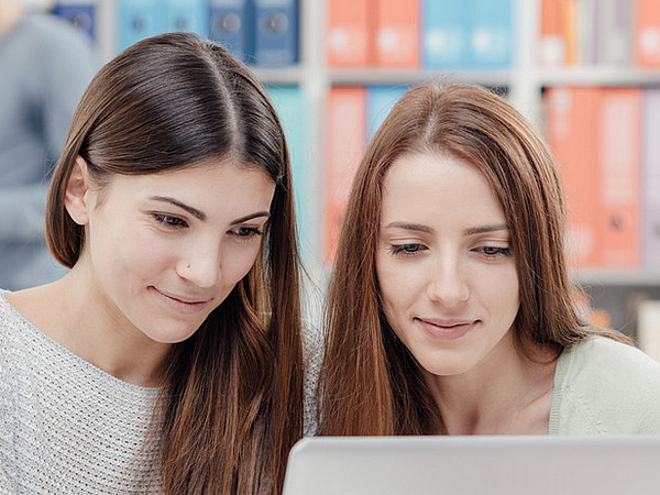 Zwei Frauen am Laptop in der Bibliothek