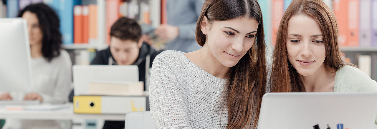 Zwei Frauen am Laptop in der Bibliothek