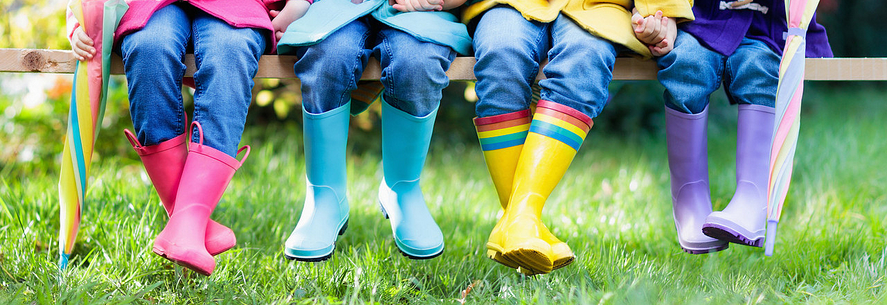4 Kinder in Gummistiefeln auf der Wiese