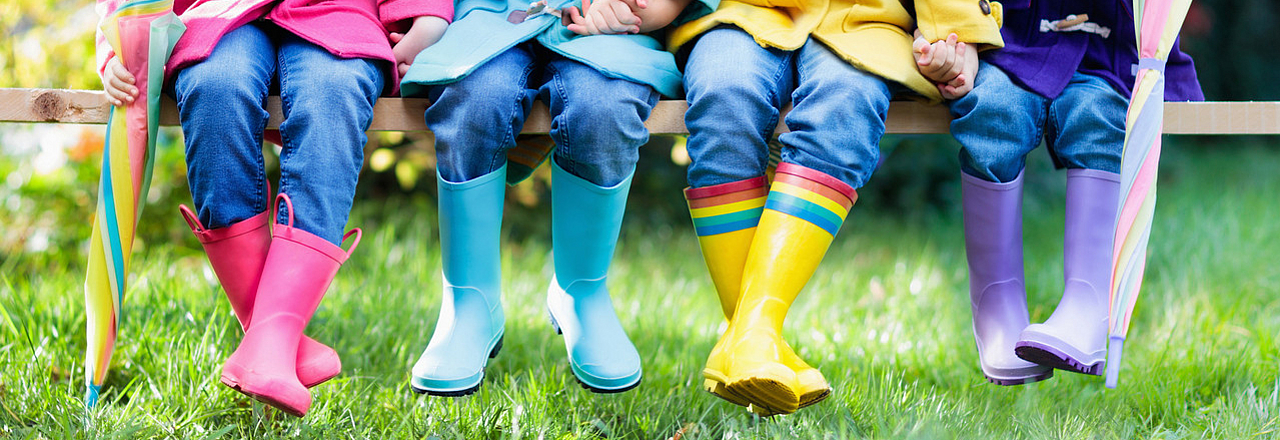 4 Kinder in Gummistiefeln auf der Wiese