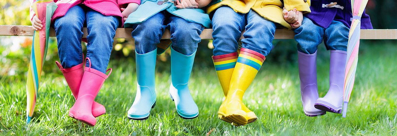 4 Kinder in Gummistiefeln auf der Wiese