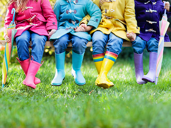 4 Kinder in Gummistiefeln auf der Wiese