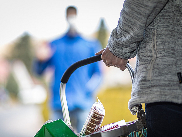 Frau trägt einen gefüllten Einkaufskorb als Sinnbild für Hilfsbereitschaft