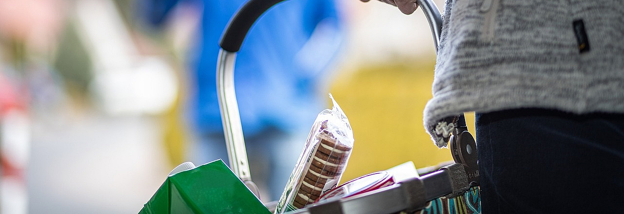 Frau trägt einen gefüllten Einkaufskorb als Sinnbild für Hilfsbereitschaft