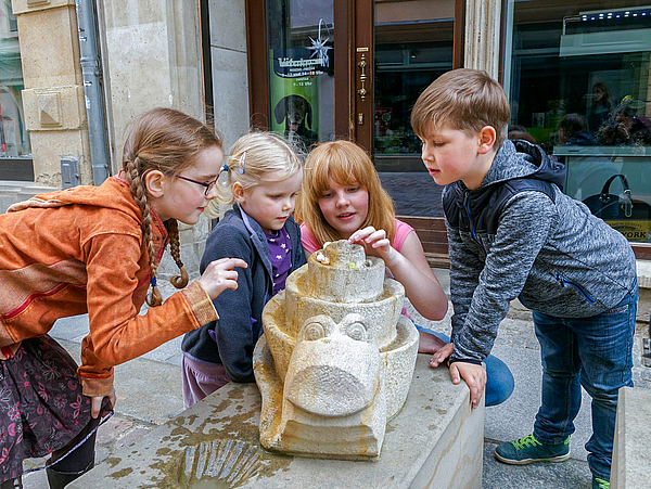 Erlebnispunkt am Bunte Steine Pfad Kinder spielen mit Murmel an einer Sandsteinschnecke