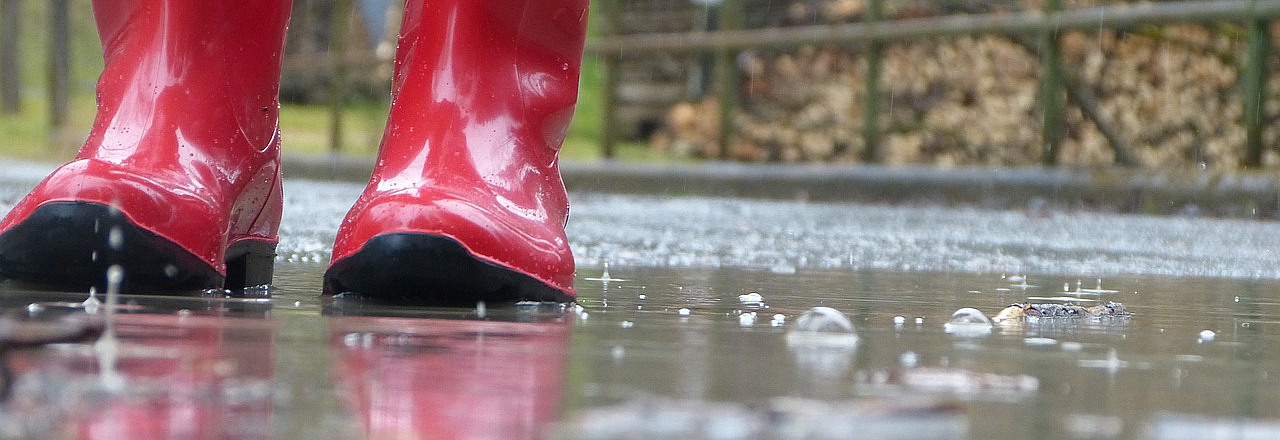 rote Gummisiefel auf nassem Grund