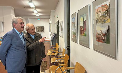 OB Lochner und der Künstler schauen sich gemeinsam die Ausstellung im Rathaus an