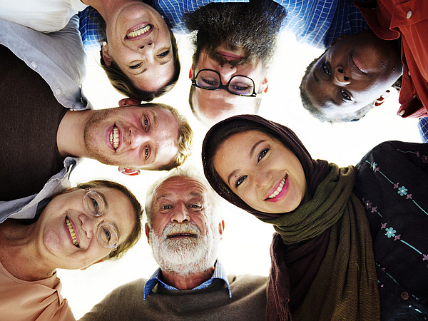 Integration und Migration Vier Menschen verschiedenen Alters und unterschiedlicher Herkunft stehen beieinander