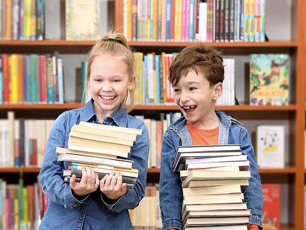 Kinder mit einem Bücherstapel in einer Bibliothek