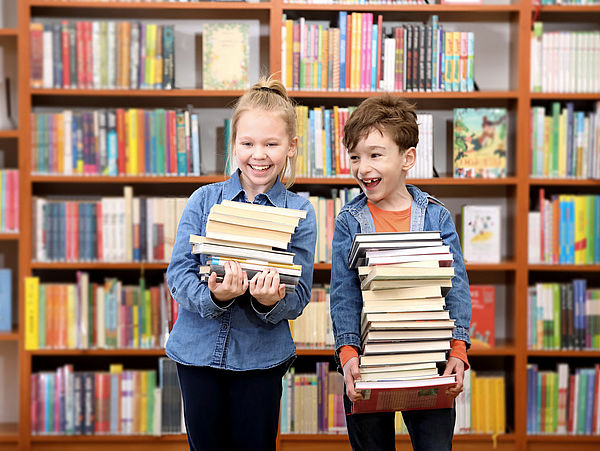 Kinder mit einem Bücherstapel in einer Bibliothek