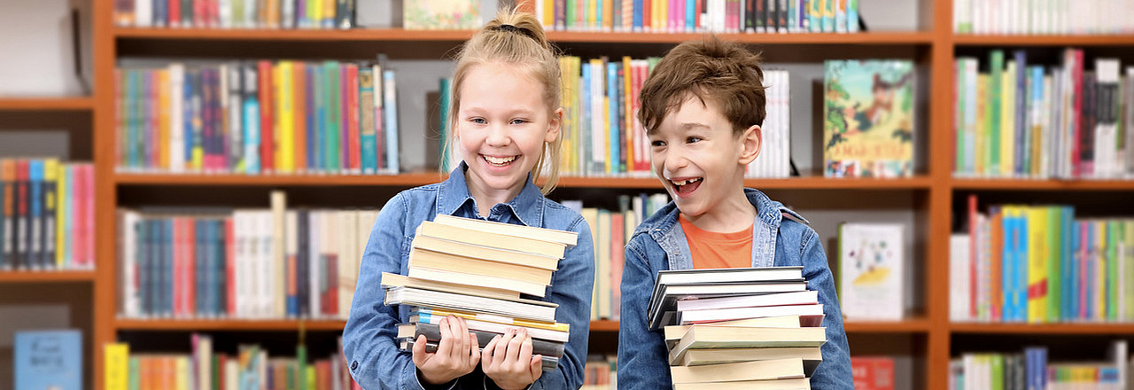 Kinder mit einem Bücherstapel in einer Bibliothek