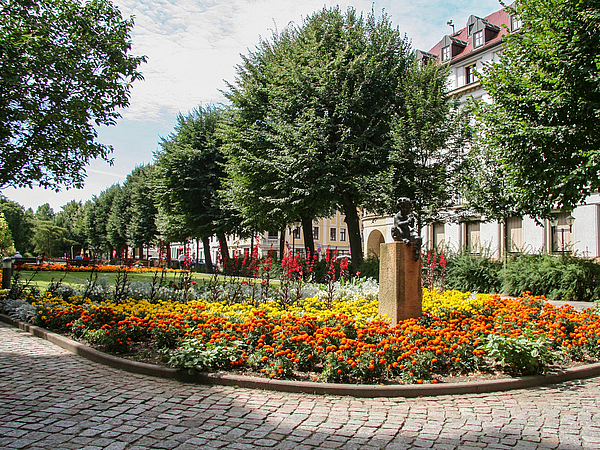 Blühende Grünanlage Grohmannstraße mit Faun-Statue