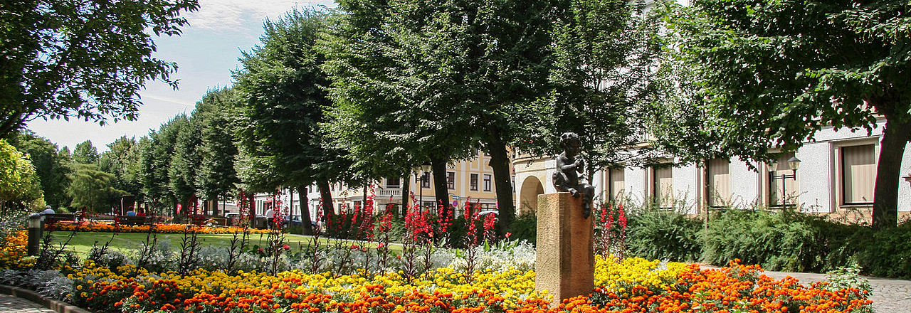 Blühende Grünanlage Grohmannstraße mit Faun-Statue