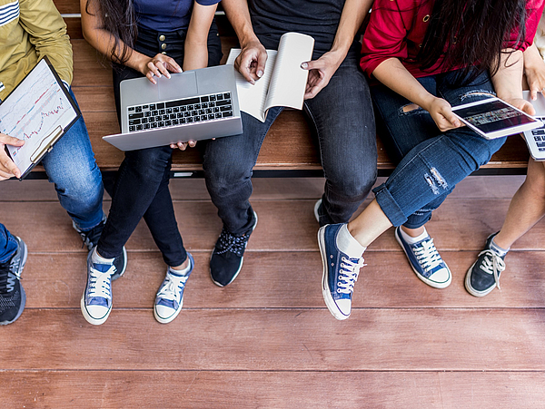 Junge Menschen sitzen zusammen mit einem Laptop