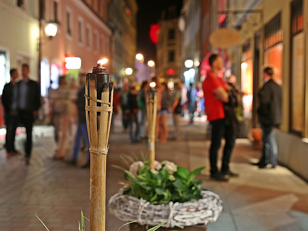 Fackel in belebter Einkaufsgasse bei Nacht