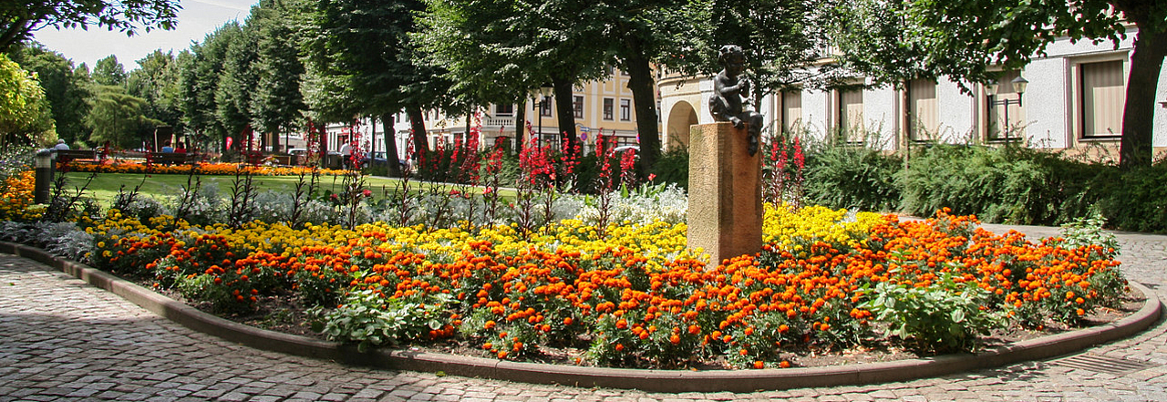 Blühende Grünanlage Grohmannstraße mit Faun-Statue