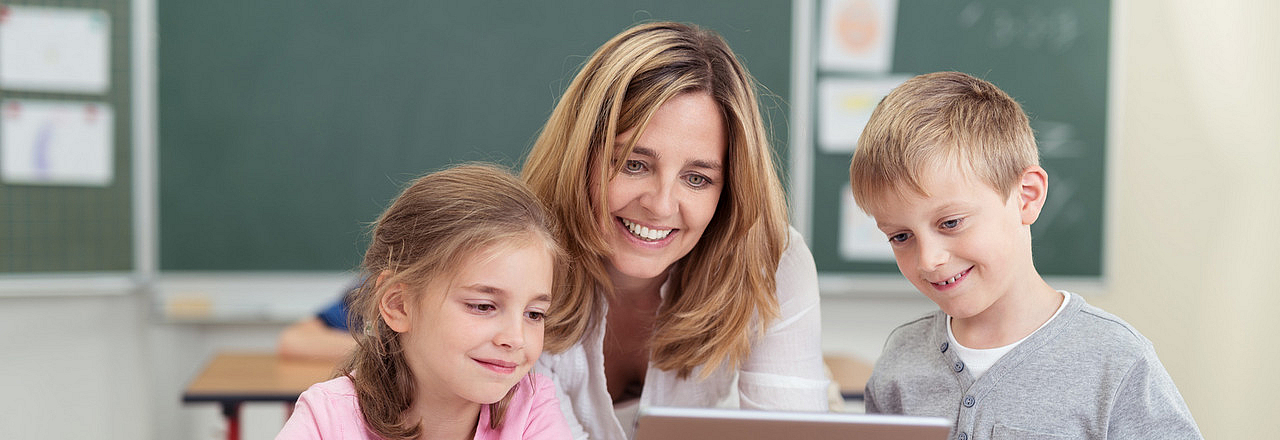 Lehrerin unterrichtet zwei Kinder im Klassenzimmer