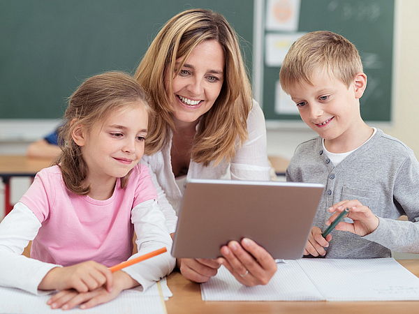 Lehrerin unterrichtet zwei Kinder im Klassenzimmer