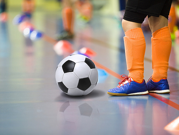 Junge spielt Fußball in einer Halle