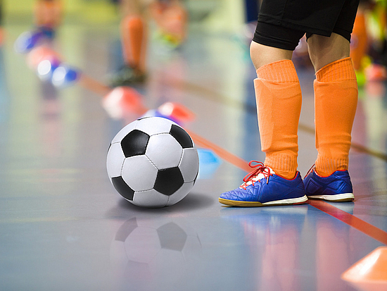 Kind spielt Fußball in einer Halle