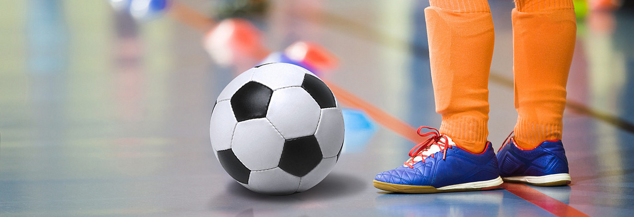 Kind spielt Fußball in einer Halle