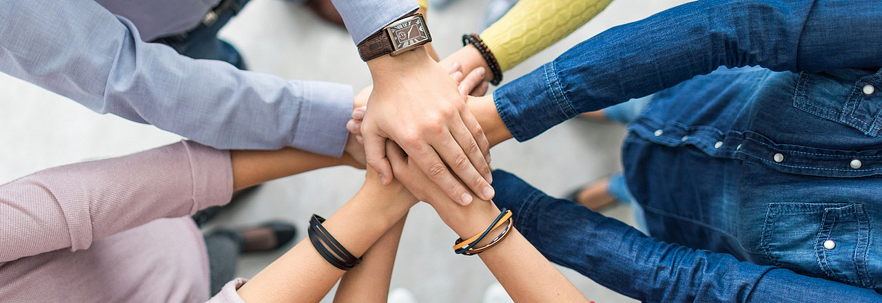 5 Menschen reichen sich die Hände als Sinnbild für Vereine in Pirna