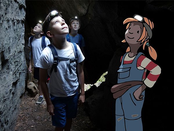 Pirnas gezeichnete Kinderbloggerin erkundet eine Höhle. Sie wurde in ein Foto mit Kindern eingezeichnet.