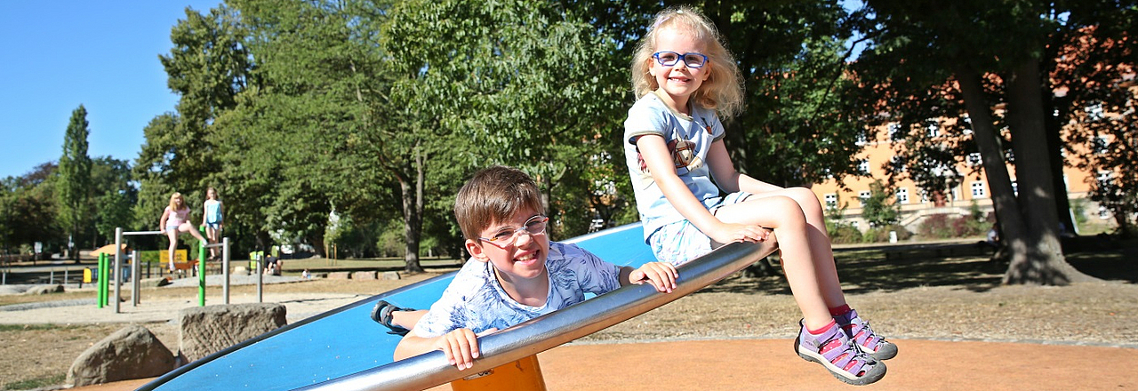 Kinder auf einer Drehscheibe auf dem Spielplatz Thälmannpark in Pirna