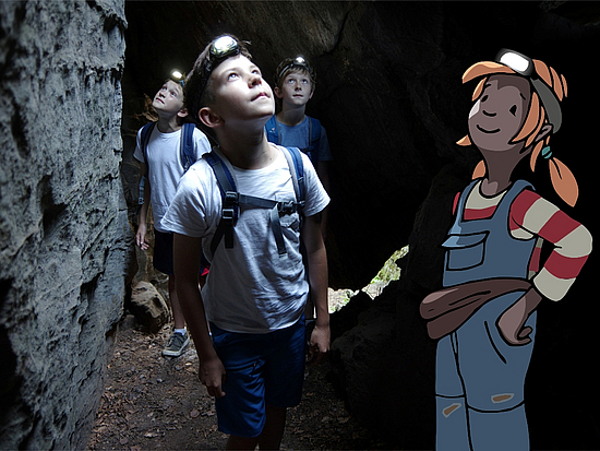 Pirnas gezeichnete Kinderbloggerin erkundet eine Höhle. Sie wurde in ein Foto mit Kindern eingezeichnet.