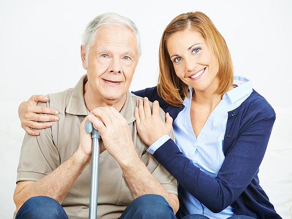 Pflegedienstmitarbeiterin unterstützt Senior mit Gehstock