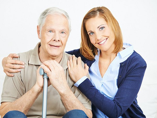 Pflegedienstmitarbeiterin unterstützt Senior mit Gehstock