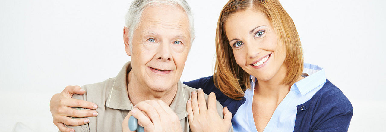 Pflegedienstmitarbeiterin unterstützt Senior mit Gehstock